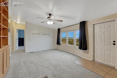 View of living room from entrance of home. Featuring brand new carpet, shiplap wall and ceiling fans. Plenty of natural light and built in bookshelves.