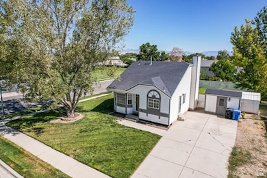 View of front of property with an outdoor structure, a chimney, concrete driveway, and a front lawn