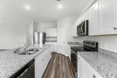 Kitchen featuring stainless steel appliances, dark wood finished floors, light stone countertops, and recessed lighting