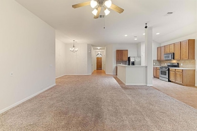 Kitchen featuring tasteful backsplash, open floor plan, brown cabinets, light colored carpet, and recessed lighting