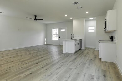 Kitchen with ceiling fan, white cabinets, light ha