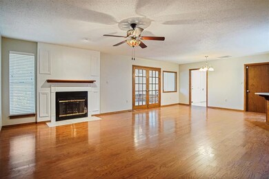 Unfurnished living room with ceiling fan with notable chandelier, light hardwood / wood-style flooring, and a textured ceiling