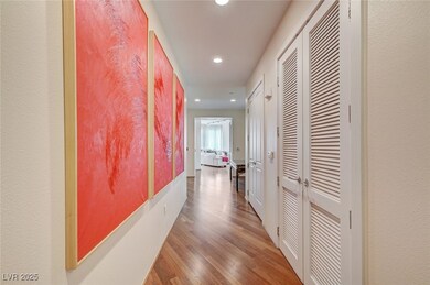 Hall with wood finished floors, recessed lighting, and a textured wall