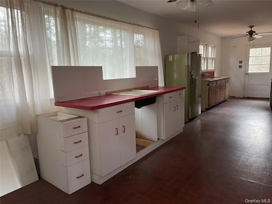 Kitchen featuring white cabinets, freestanding refrigerator, a ceiling fan, and brick patterned flooring