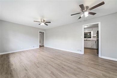 Spare room with ceiling fan, wood finished floors, a sink, and baseboards