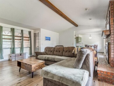 Living area featuring light wood-type flooring, a brick fireplace, and a textured ceiling