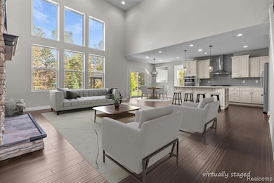 Living area with recessed lighting, a towering ceiling, and dark wood-style floors