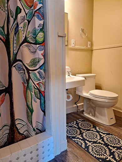 Full bath with wood finished floors, a shower wit
