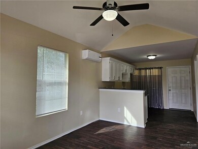 Kitchen with ceiling fan, dark hardwood / wood-style flooring, lofted ceiling, a wall unit AC, and white cabinets