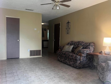 Living room with a ceiling fan, a textured ceiling