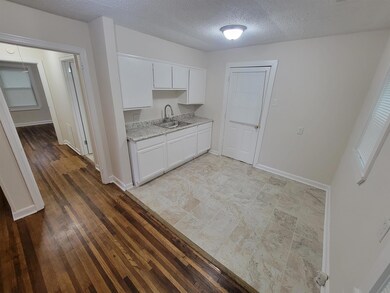 Kitchen with sink, light stone counters, a texture