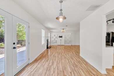 Elegant dining area featuring a classic chandelier, bright window with blinds for ample natural light, and attractive wood-look flooring