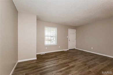 Spare room featuring a textured ceiling and dark wood finished floors