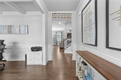 Corridor with ornamental molding, stairway, dark wood-style flooring, a wainscoted wall, and an office area