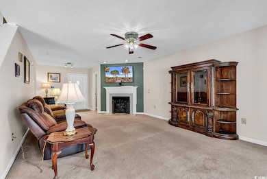 Carpeted living area with a ceiling fan, baseboard
