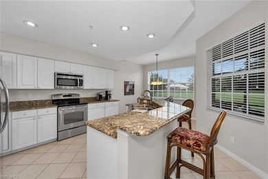 Eat in Kitchen featuring appliances with stainless steel finishes, a sink, light tile patterned floors, white cabinetry, and a kitchen bar