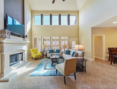 This lovely living room is open and bright! Featuring soaring high ceilings with ceiling fan, beautiful 
ceramic tile flooring, an elegant mantle and fire place, large windows providing a beautiful view of the backyard and tons of natural light in throughout the day!