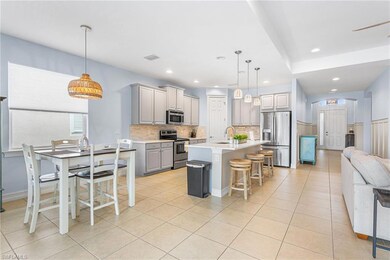 Kitchen with appliances with stainless steel finishes, decorative backsplash, gray cabinetry, open floor plan, and light countertops