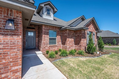 View of exterior entry with brick siding, roof with shingles, and a yard