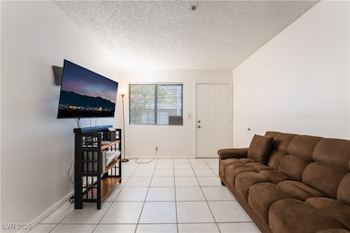 Living area featuring a textured ceiling, light ti
