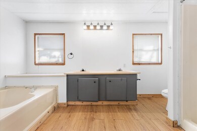 Full bathroom featuring double vanity, light wood finished floors, and a garden tub
