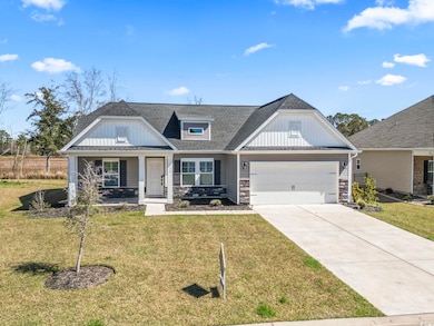 Craftsman-style house featuring an attached garage, stone siding, driveway, and a front yard