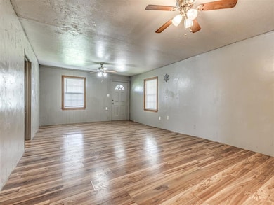 Empty room with a ceiling fan, wood finished floors, and a textured ceiling
