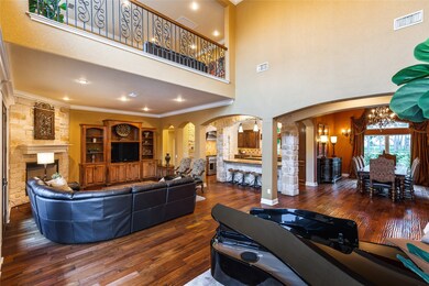 The main living space at the heart of the home blends seamlessly between the formal dining room, formal living room, and a cozy family room, with a soaring ceiling extending up to the second-floor game room balcony.