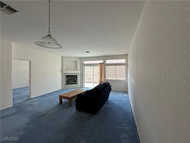 Living room with a textured wall, visible vents, carpet floors, and a tile fireplace
