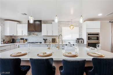 Kitchen with a breakfast bar, white cabinets, decorative light fixtures, and decorative backsplash