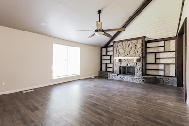 Unfurnished living room featuring a ceiling fan, wood finished floors, and a fireplace