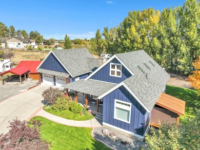 View of front facade with a shingled roof, board and batten siding, covered porch, a garage, and a front lawn