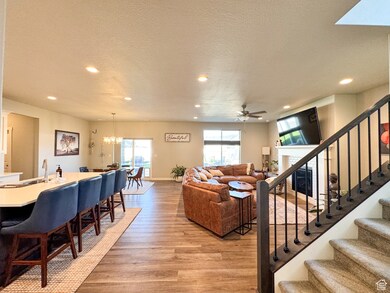 Living area featuring light wood-style flooring, a textured ceiling, a chandelier, stairs, and ceiling fan