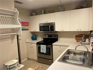 Kitchen featuring stainless steel appliances, light countertops, light tile patterned flooring, and white cabinets