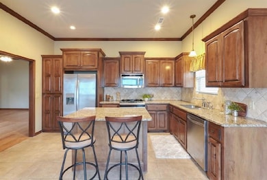 Kitchen featuring stainless steel appliances, a center island, sink, ornamental molding, and tasteful backsplash