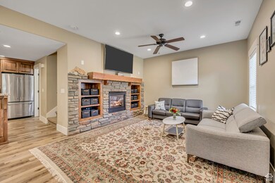 Living room featuring recessed lighting, light wood-style floors, ceiling fan, and a stone fireplace