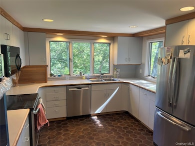 Kitchen with appliances with stainless steel finishes, white cabinets, light countertops, and recessed lighting
