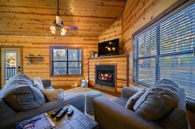 Living room featuring wood ceiling, ceiling fan, lofted ceiling, and wood walls