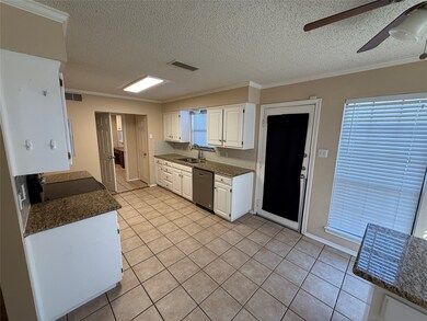 Kitchen with ornamental molding, dark stone countertops, white cabinetry, a textured ceiling, and light tile patterned flooring