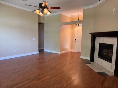 Living room featuring crown molding, dark wood-style floors, a ceiling fan, a fireplace