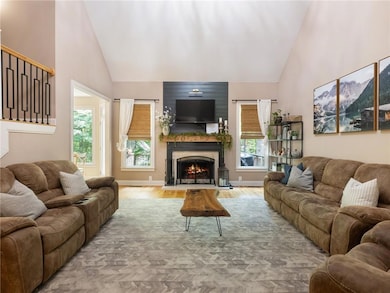 Living area featuring high vaulted ceiling, a warm lit fireplace, and wood finished floors