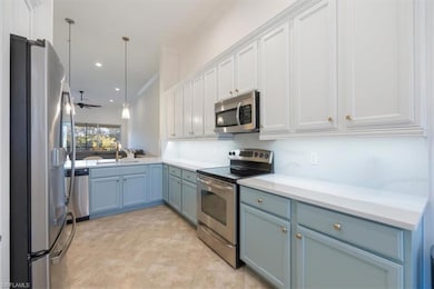 Kitchen with appliances with stainless steel finishes, blue cabinetry, a ceiling fan, white cabinets, and ornamental molding
