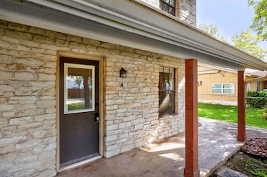 Doorway to property with stone siding and a patio