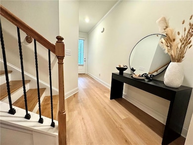 Corridor featuring ornamental molding, wood finished floors, baseboards, and stairs