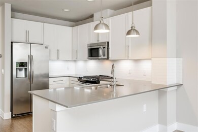 Kitchen featuring stainless steel appliances, a peninsula, a sink, decorative backsplash, and decorative light fixtures