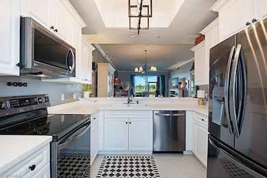 Kitchen with appliances with stainless steel finishes, a chandelier, white cabinets, and decorative light fixtures