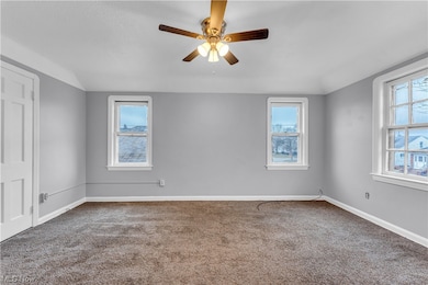 Carpeted empty room featuring plenty of natural light and ceiling fan