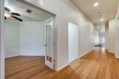 Hallway with light wood-style flooring and recessed lighting