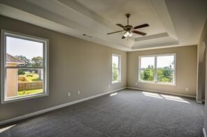 Unfurnished room with a tray ceiling, ceiling fan,