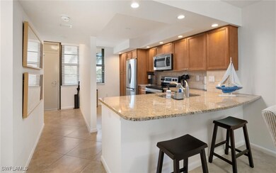 Kitchen with light stone counters, appliances with stainless steel finishes, kitchen peninsula, and a breakfast bar area